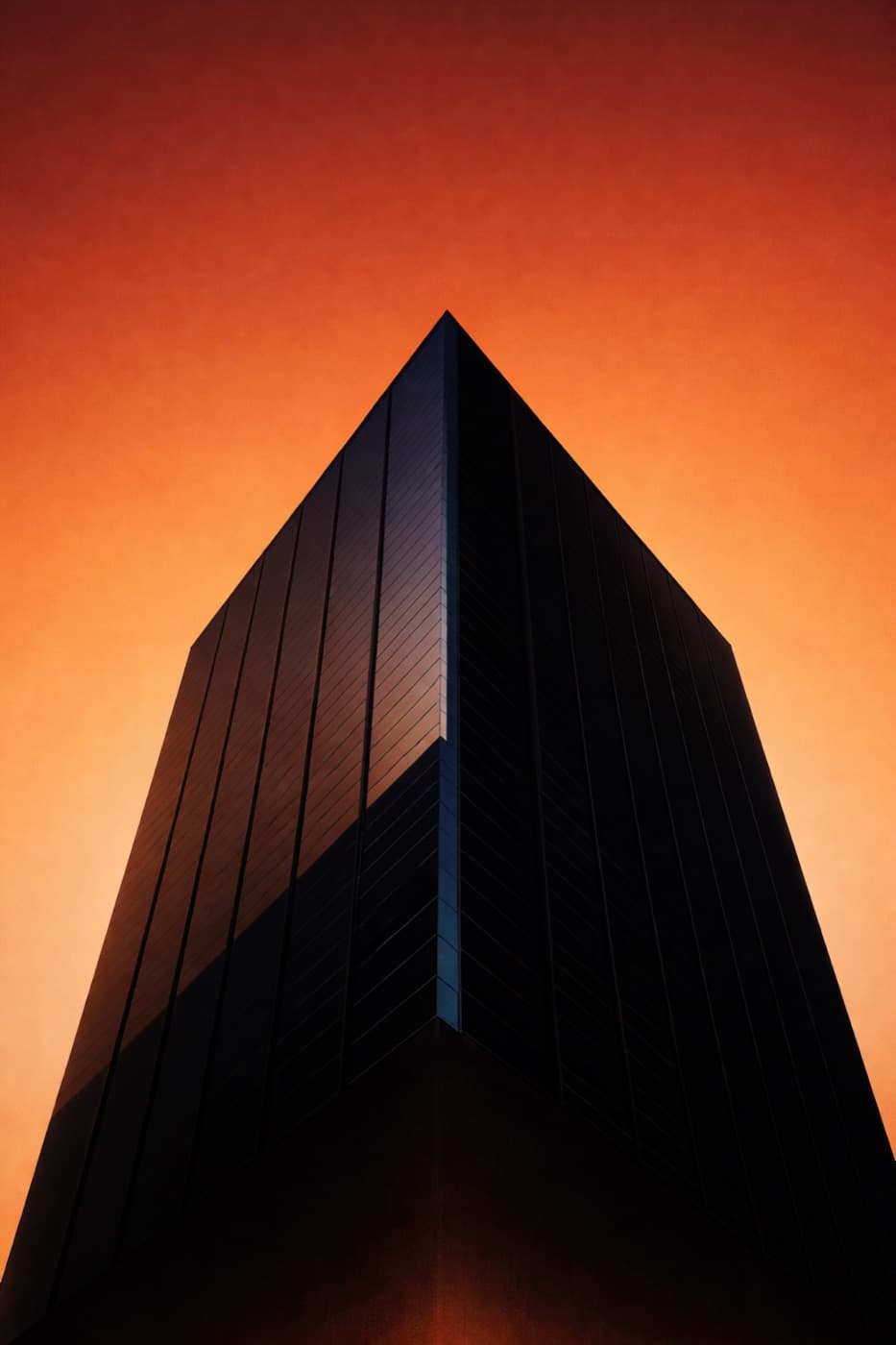 Torre corporativa recortada contra um céu alaranjado ao entardecer